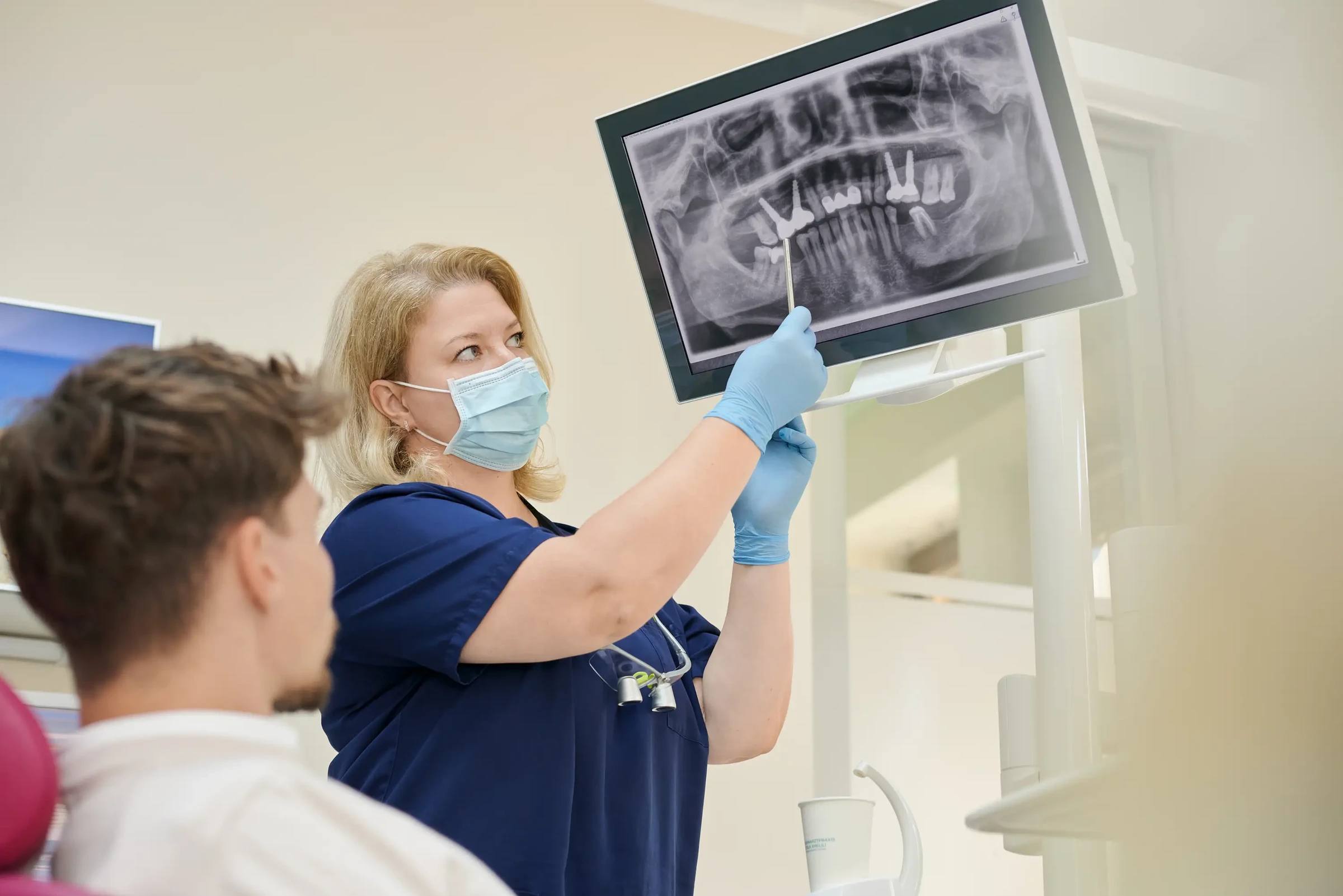 Zahnärztin bespricht das Röntgenbild mit einem Patienten