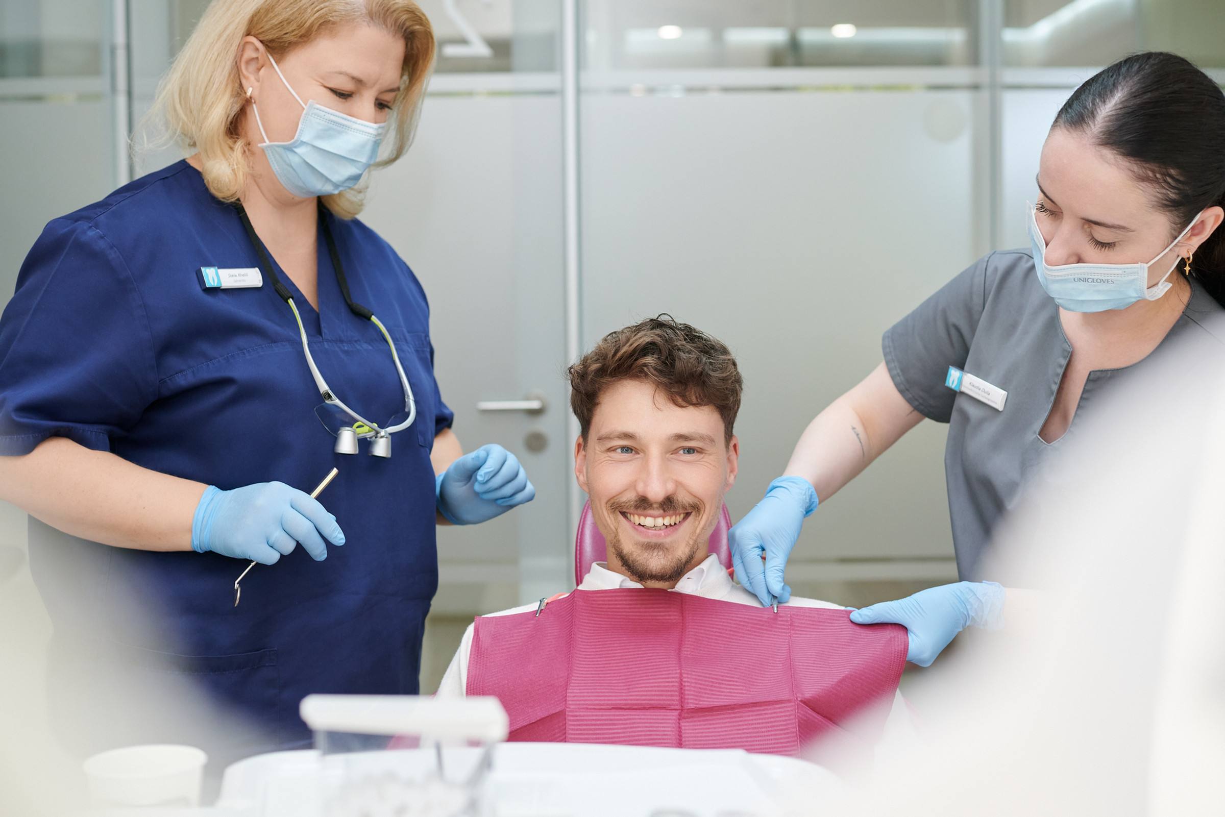 Behandlung im Team: Zahnärztin und Assistenz mit Patient