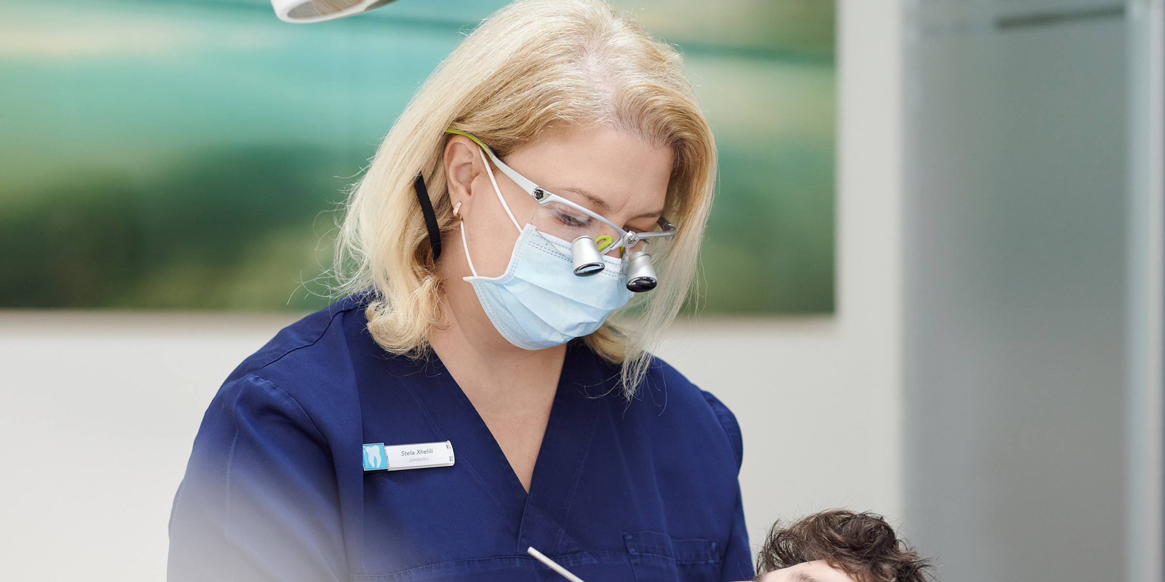 Zahnärztin mit Lupenbrille bei der Behandlung